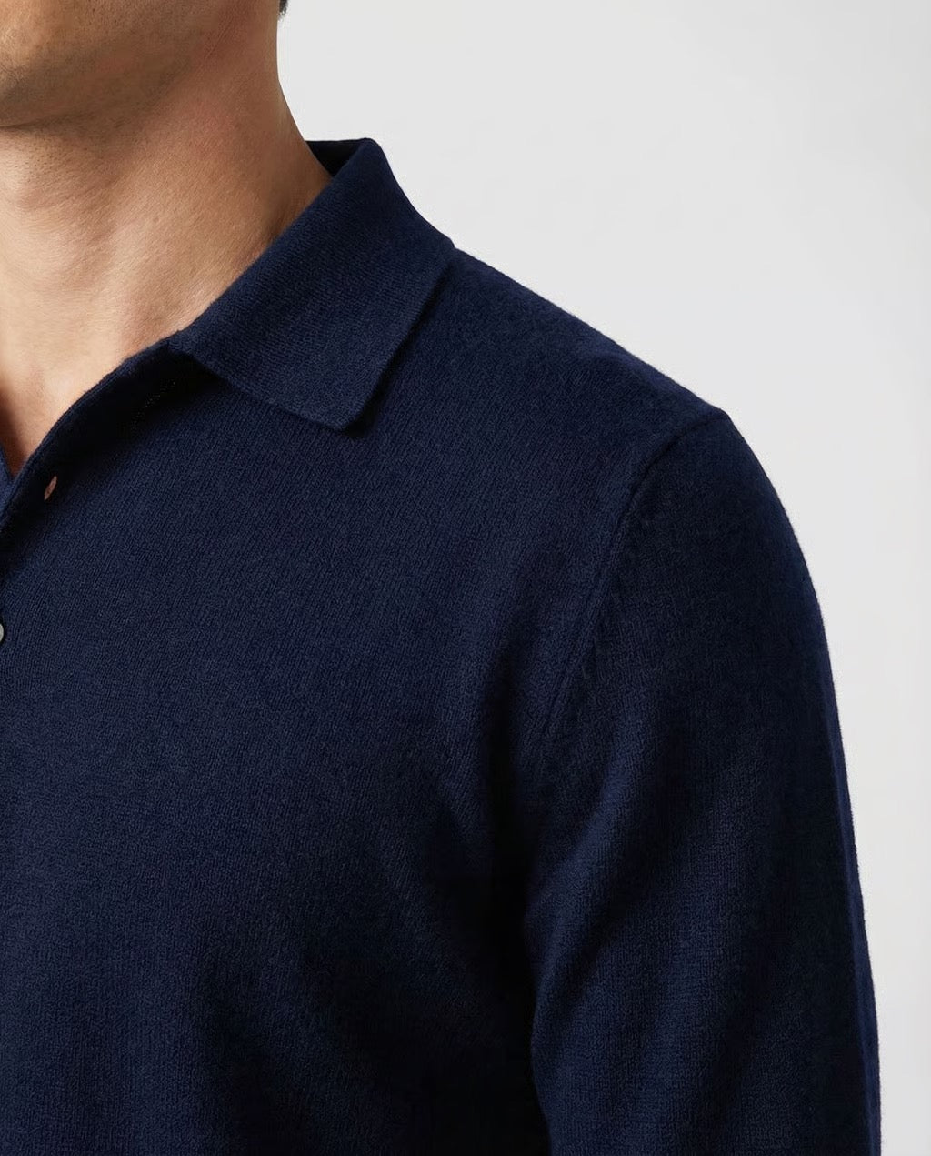 Navy blue long-sleeve shirt worn by a person on a light gray background